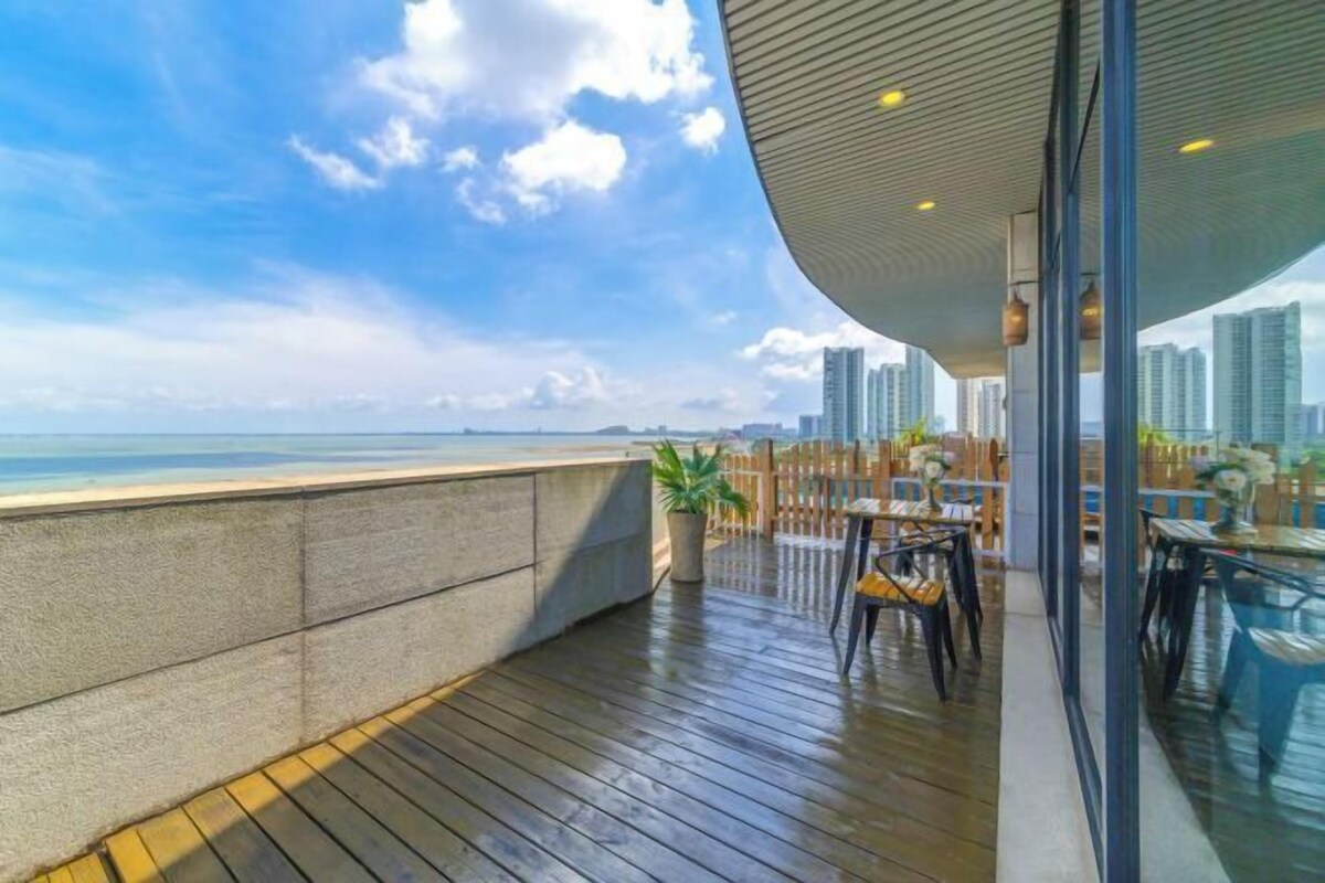 A balcony with a view of the ocean and city skyline.