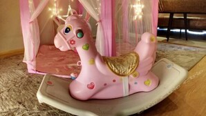 A pink toy horse with a saddle and heart decorations inside a pink and white play tent with a canopy. - Vaikuha Seaview Hotel (Beihai)