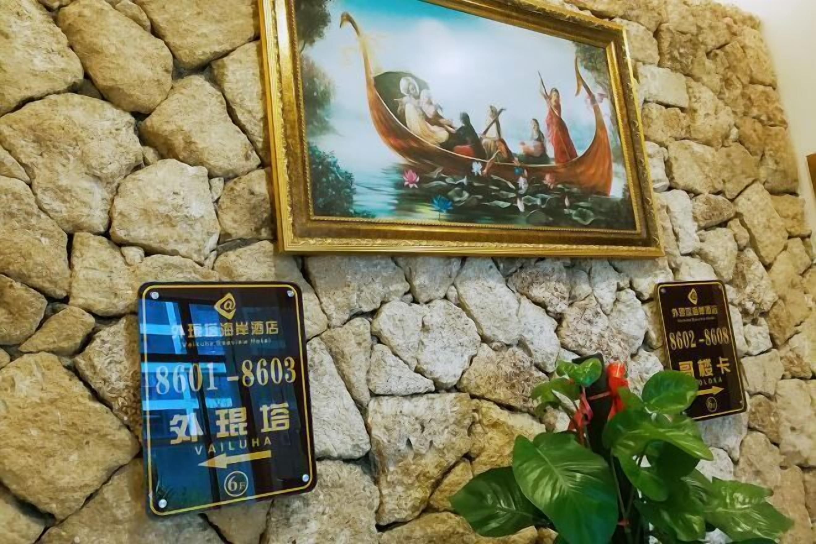 A stone wall with a framed painting of a boat and two signs.