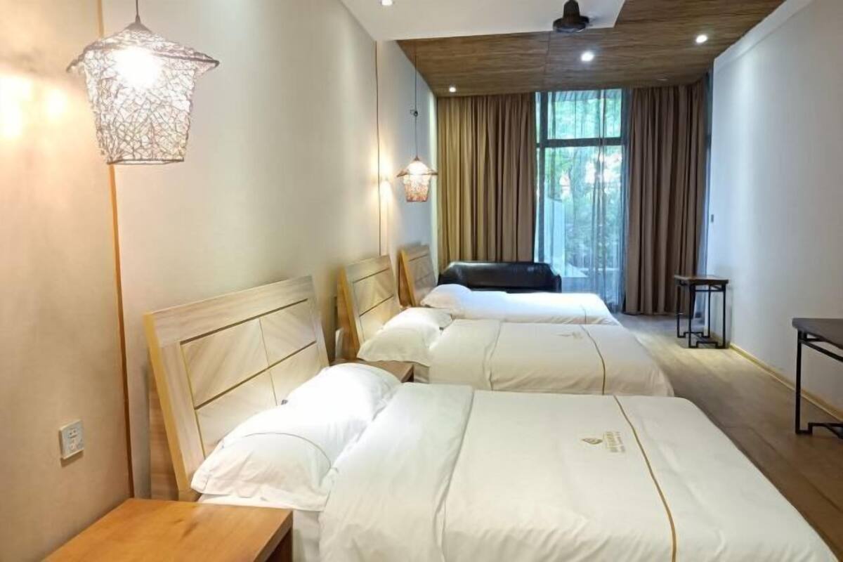 Habitación de hotel con dos camas, techo de madera, lámpara colgante y ventana con cortinas.