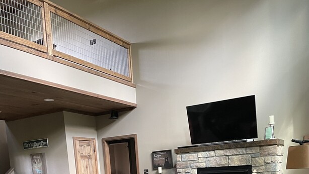 A spacious living room with a fireplace, leather furniture, a television, and a balcony. - Relax and Unwind on the Caddo River in Beautiful Arkansas! Book now! (Amity)