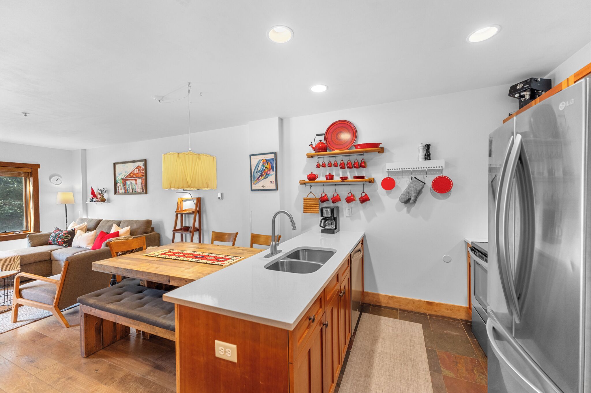 A modern kitchen with a central island, stainless steel appliances, and a dining area with a wooden table and bench.