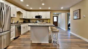 Una cocina moderna con armarios blancos, electrodomésticos de acero inoxidable y una isla grande con taburetes.