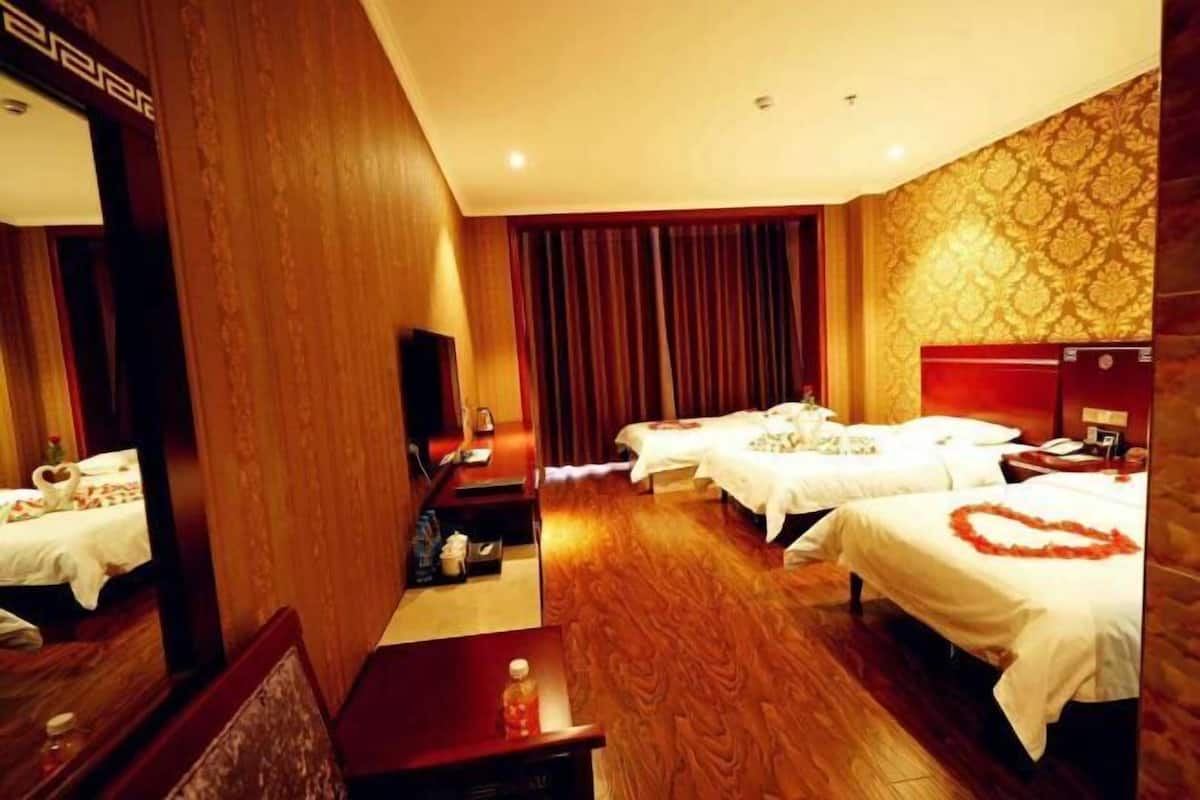 A hotel room with a wooden floor, a large mirror, a desk, and two beds with white linens.