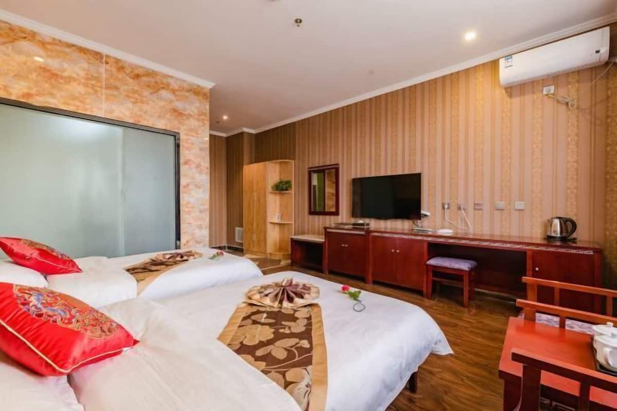A hotel room with two beds, a desk, a television, and a wardrobe.