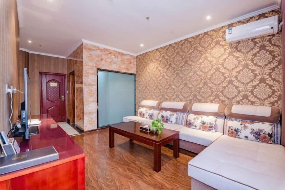 A hotel lobby with a reception desk, a sofa set, and a patterned wall.