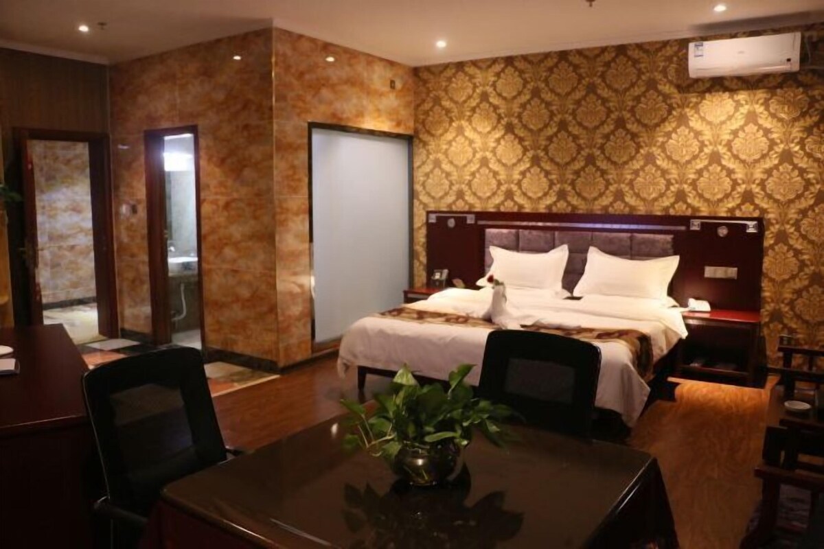A hotel room with a bed, bedside table, and a desk with chairs.
