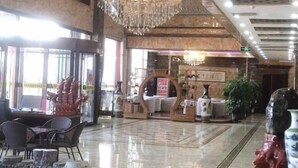 Un hall amplio con una araña, una recepción y una zona de estar con sillas.