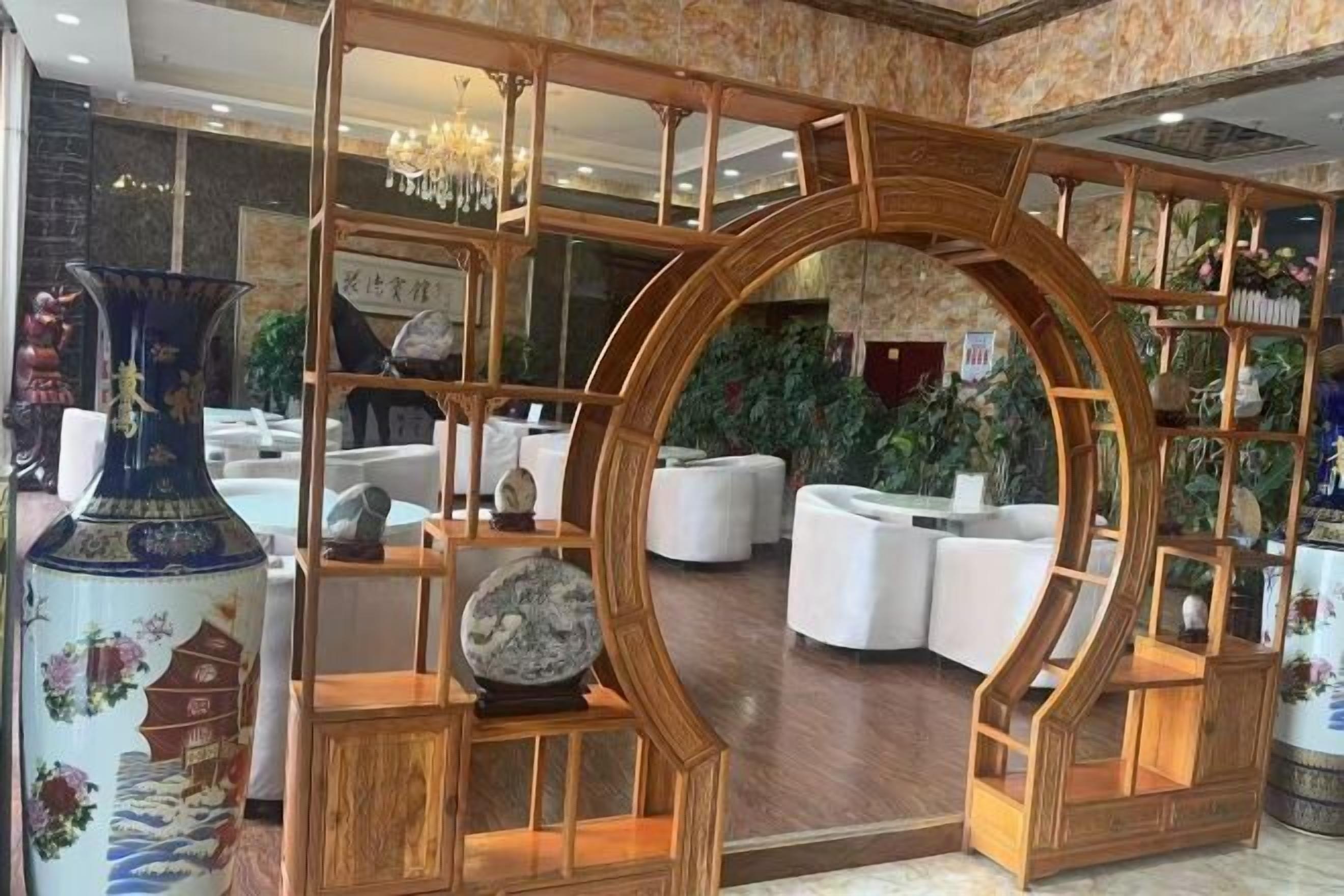 A traditional-style interior with a wooden partition, white furniture, and decorative items including a vase and a shelf with plants.