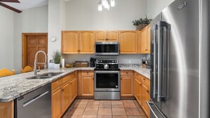 A modern kitchen with wooden cabinets, stainless steel appliances, a granite countertop, and a built-in oven. - Hidden River Lodge #5998 by Summit County Mountain Retreats (Keystone)