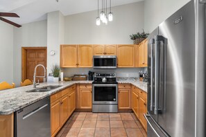 A modern kitchen with wooden cabinets, stainless steel appliances, a granite countertop, and a built-in oven. - Hidden River Lodge #5998 by Summit County Mountain Retreats (Keystone)
