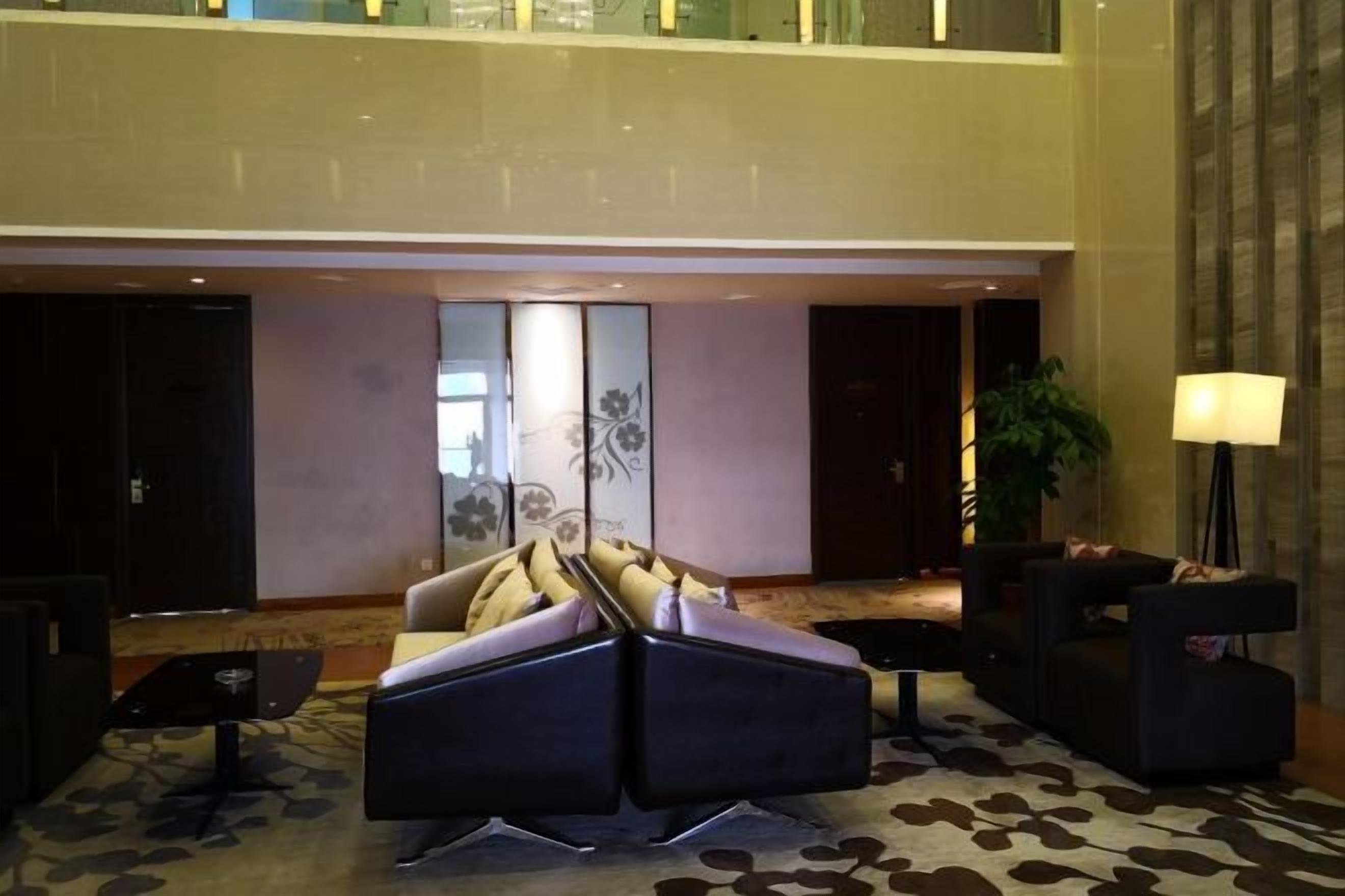 A lobby with a sofa set, a coffee table, and a lamp.