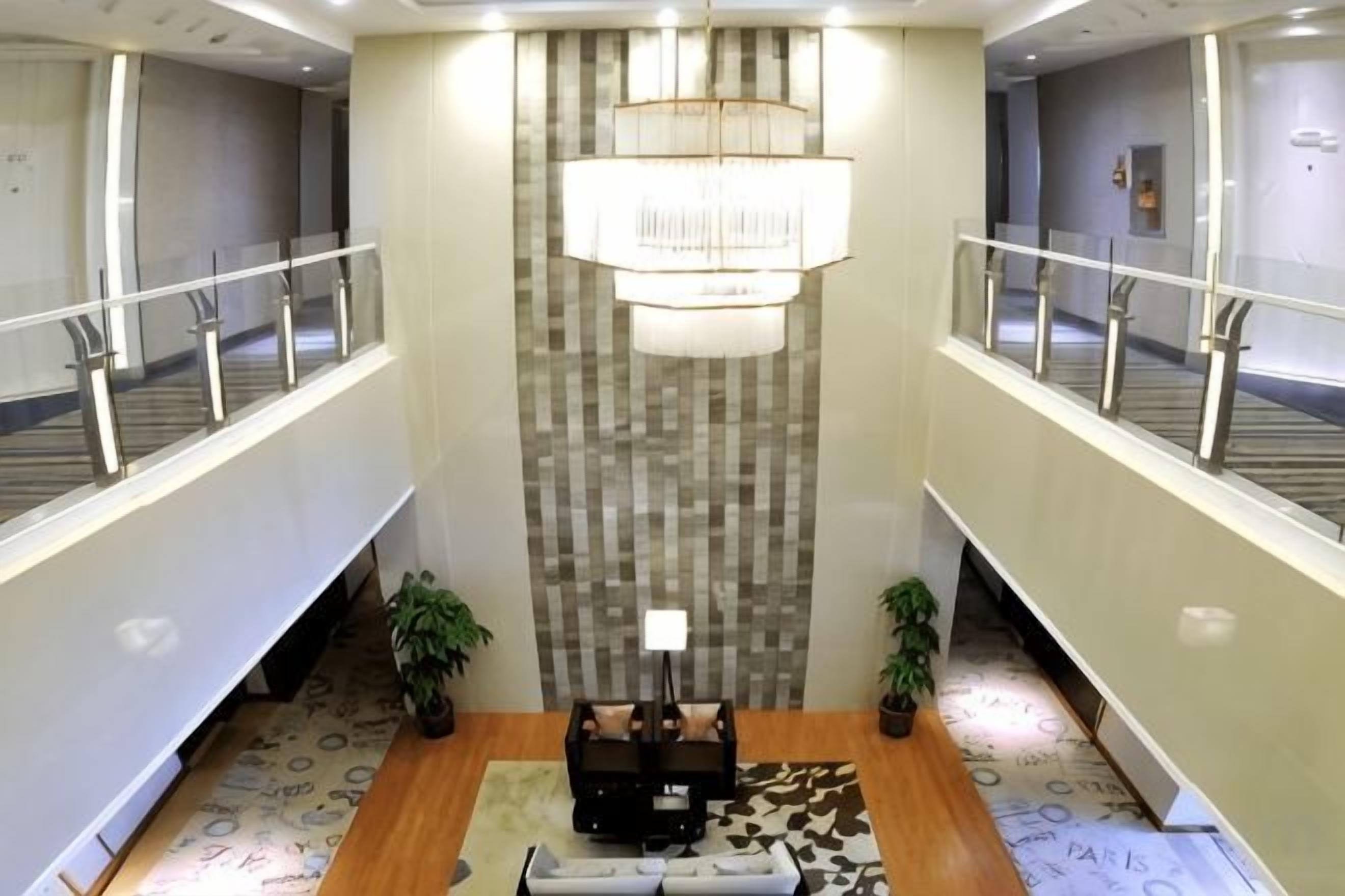 A hotel lobby with a chandelier, a reception desk, and a patterned wall.