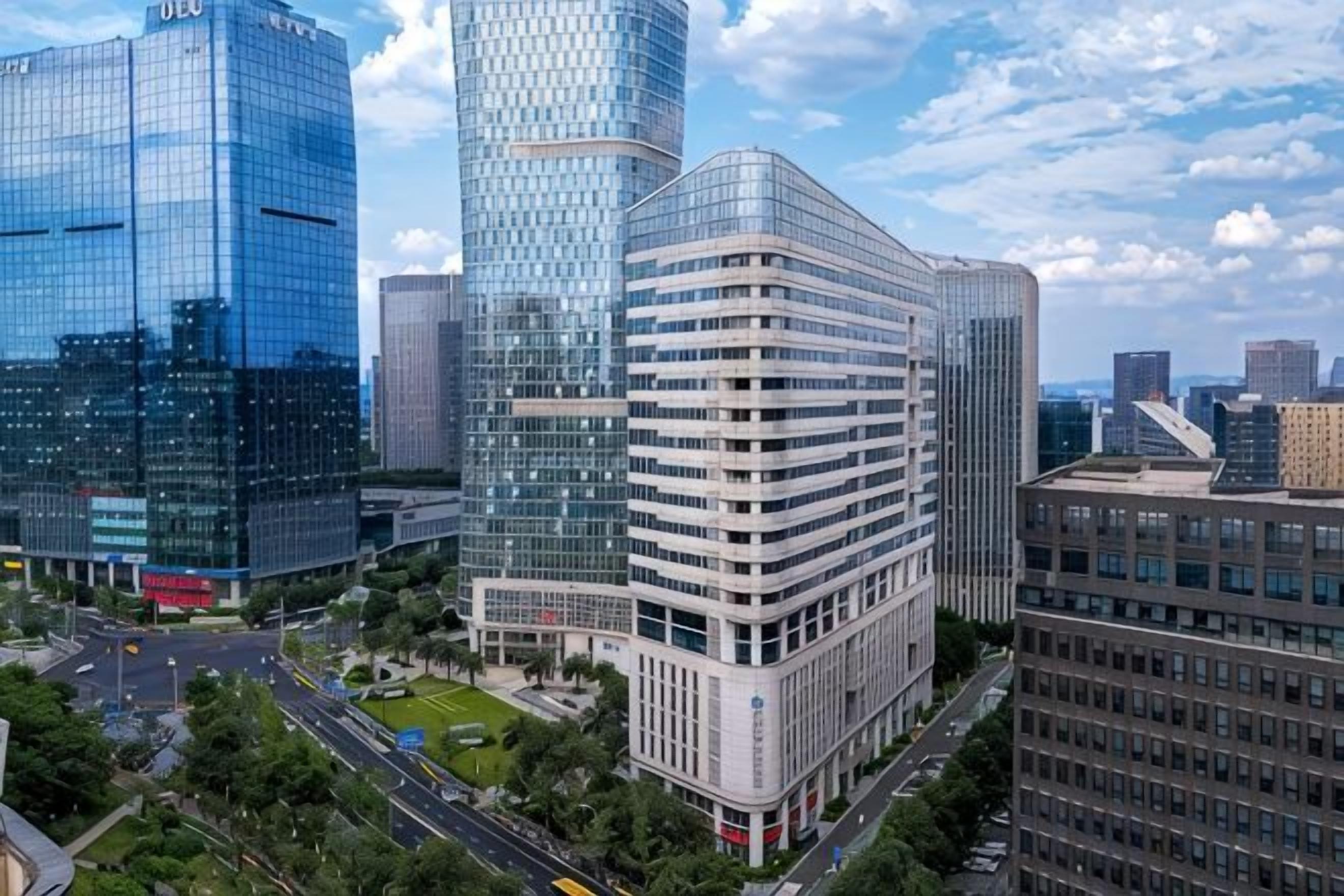 A modern urban skyline with high-rise buildings, including a distinctive curved glass structure and a rectangular building with a flat roof.