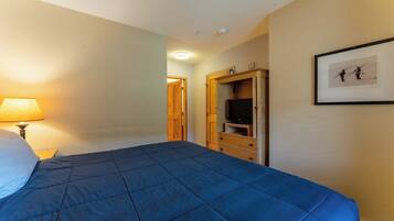 Une chambre d’hôtel avec un grand lit, une télévision, une armoire en bois et un tableau encadré au mur.