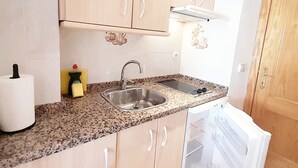 A compact kitchen with a granite countertop, stainless steel sink, and a built-in oven.