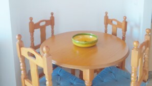 A dining table with a bowl, surrounded by wooden chairs with blue cushions.