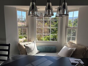 Ein Zimmer mit großem Fenster, einem Tisch mit Notizbuch und einem Stuhl.