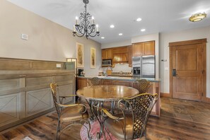 A dining area with a round table, chairs, and a chandelier.