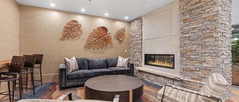 A modern lounge area with a stone fireplace, a sofa, and a round coffee table.