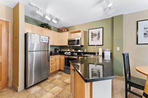 A modern kitchen with stainless steel appliances, wooden cabinets, and a granite countertop. - Silver Mill #8177 by Summit County Mountain Retreats (Keystone)
