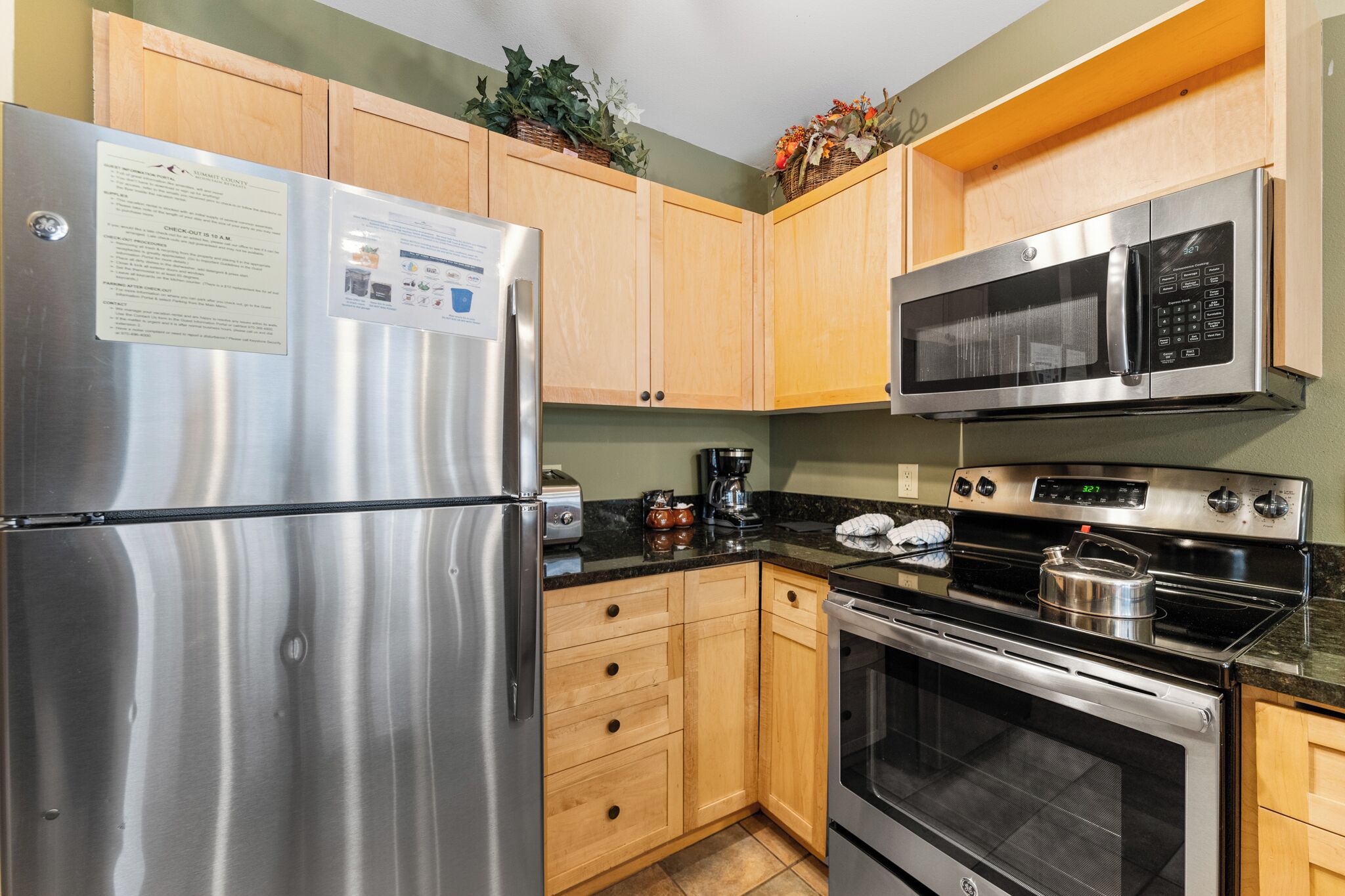 A kitchen with stainless steel appliances, wooden cabinets, and a granite countertop.