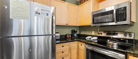 A kitchen with stainless steel appliances, wooden cabinets, and a granite countertop.