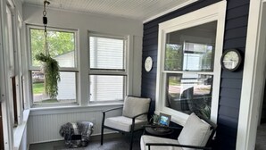 A room with a large window, a chair, a small table, and a hanging plant.