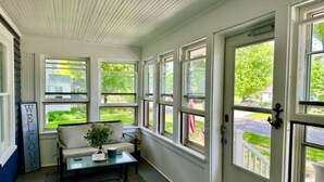 A sunroom with a sofa, coffee table, and a 'WELCOME' sign.