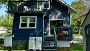A two-story house with a balcony, a front porch, and a small garden area.