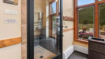 A steam room entrance with a glass door, a towel rack, and a sign indicating the room is for steam use.