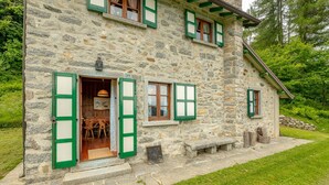 A stone building with green shutters, a wooden door, and a number '25' sign. - Il Salice by Wonderful Italy (Bellagio)