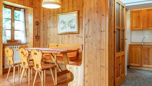 A wooden interior with a dining table and chairs, a framed picture on the wall, and a kitchen area with wooden cabinets. - Il Salice by Wonderful Italy (Bellagio)