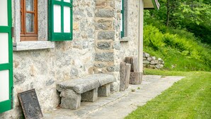 A stone building with green window frames and a stone bench along a stone pathway. - Il Salice by Wonderful Italy (Bellagio)