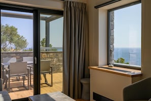 Enjoy a serene view of the sea from this room's large window, featuring a comfortable seating area and a small table.