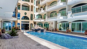 A multi-level hotel with a central pool area, outdoor seating, and a view of the surrounding landscape. - Tiara Sands condo excelente ubicación (Mazatlán)