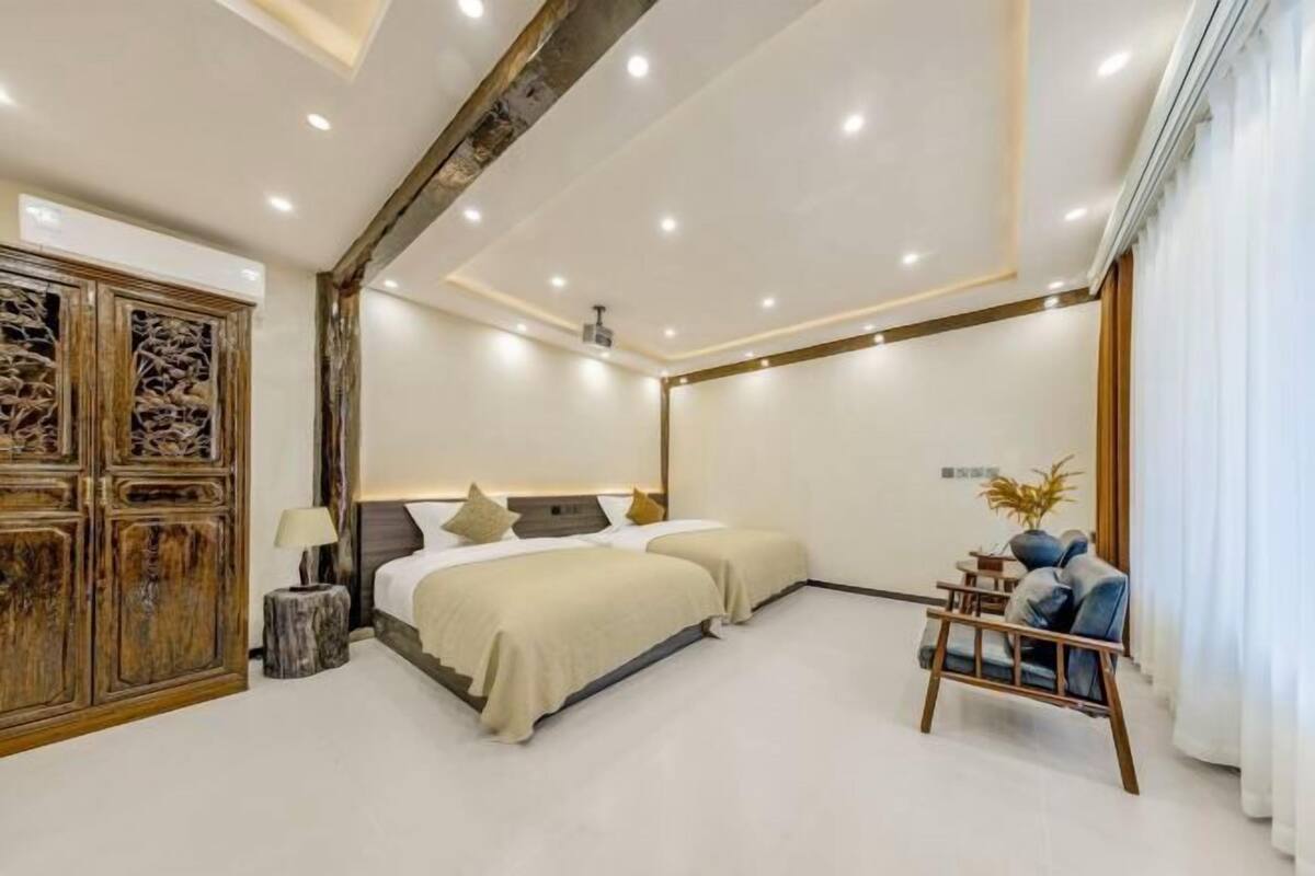 Una habitación de hotel moderna con dos camas, un armario de madera, una mesita pequeña y una silla.