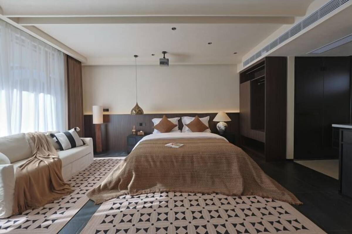 Una habitación de hotel moderna con una cama grande, un sofá, una mesita de noche y un escritorio.
