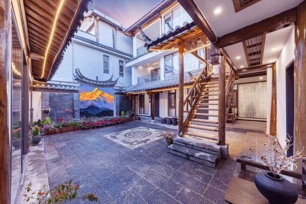 Un patio tradicional con escalera de madera, suelo de piedra y un mural.