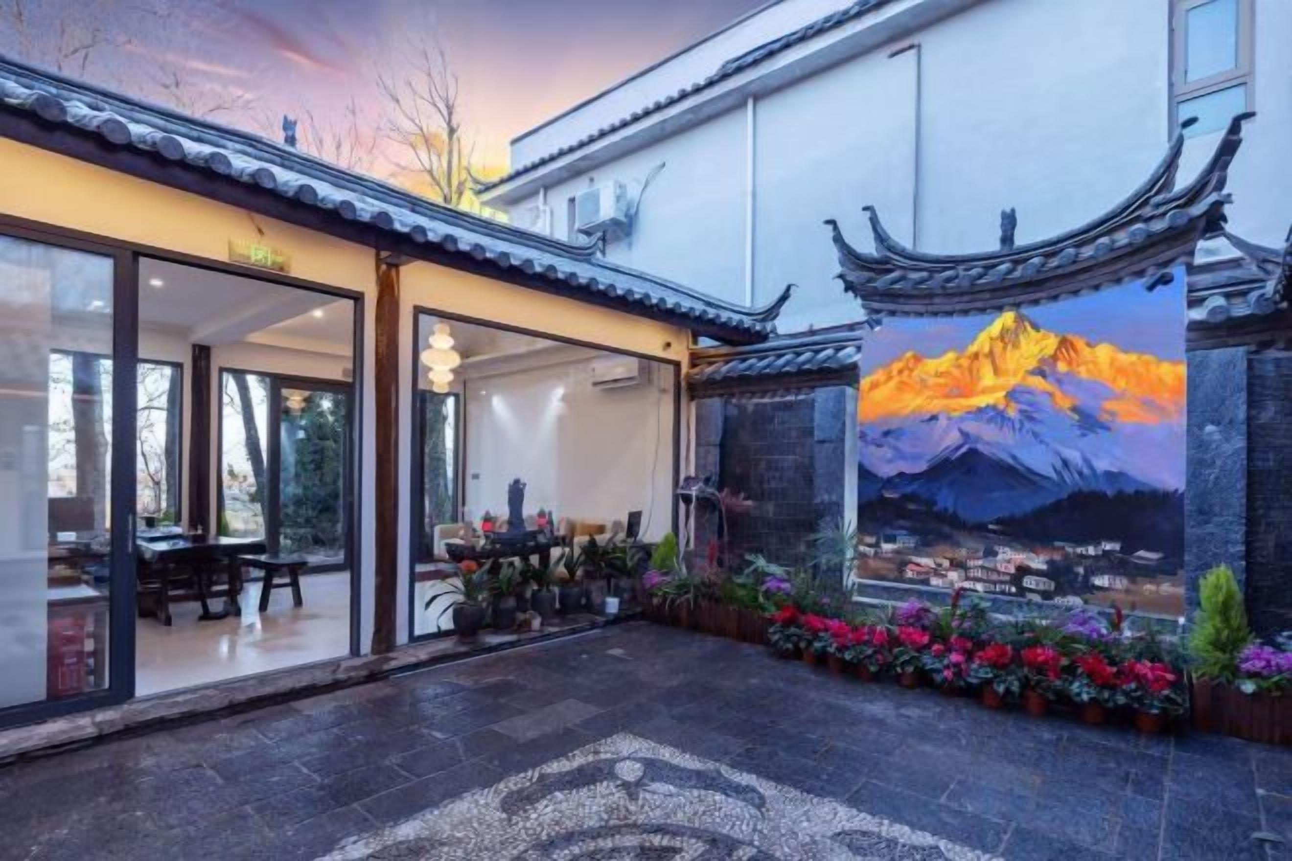 A traditional building with a dining area, a mural of a mountain, and a courtyard with potted plants.