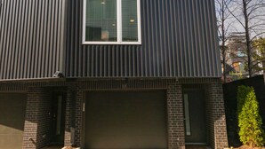 Um edifício moderno de vários andares, com fachada escura, várias janelas e entrada para a garagem.