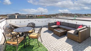 Um terraço no topo com móveis de exterior, uma mesa redonda e vista para a paisagem urbana.