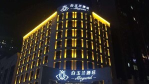 A hotel with a modern facade, illuminated signage, and a prominent logo. - Magnotel Hotel (Weinan Duhua Road Haixing City) (Weinan)