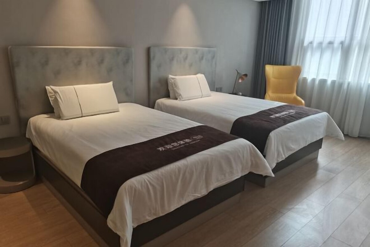 Une chambre d’hôtel avec deux lits, une chaise et une lampe.