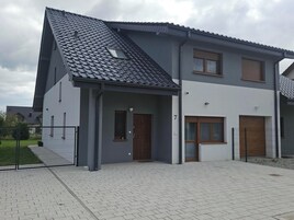 Une maison à deux étages avec un toit gris, une petite fenêtre au premier étage et le chiffre « 7 » peint sur le mur.