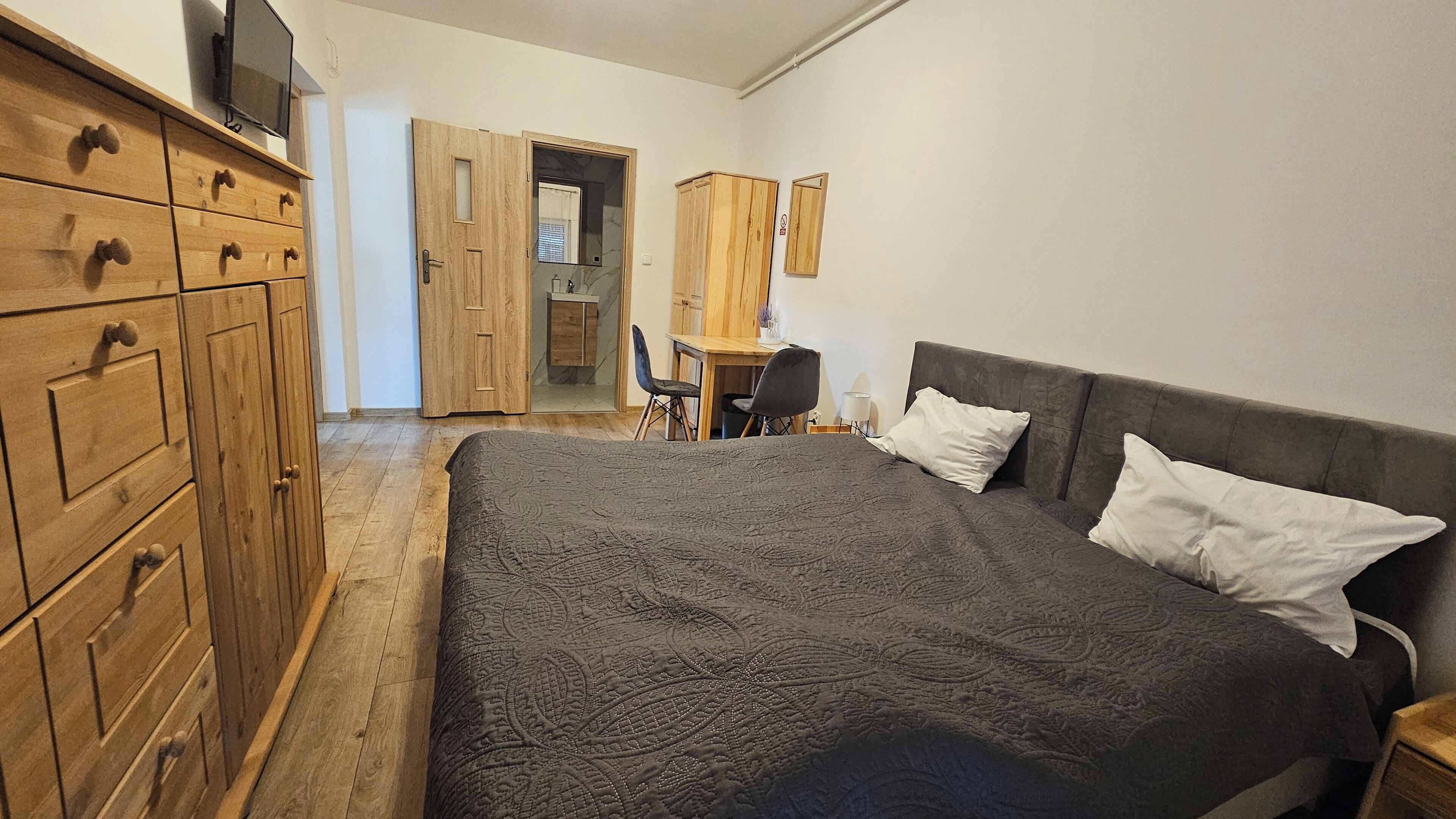 Ein Schlafzimmer mit einem großen Bett, einem Holzschrank und einem Schreibtisch mit Stuhl.