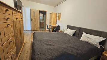 Ein Schlafzimmer mit einem großen Bett, einem Holzschrank und einem Schreibtisch mit Stuhl.