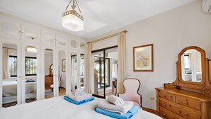 A spacious bedroom with a large bed, a wooden dresser, and a mirror. - Villa Xula - Marbella Club (Marbella)