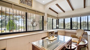 A room with a large desk, a chair, and a view of the outdoors through large windows. - Villa Xula - Marbella Club (Marbella)