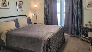 Une chambre à coucher avec un lit, une table de chevet, une lampe et une commode.